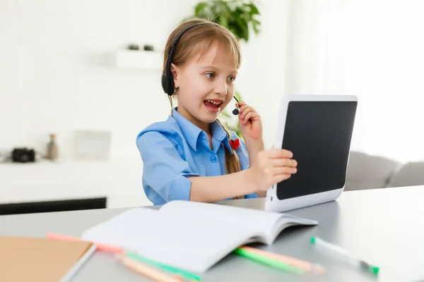 Cute little girl siedzi przy stole z laptopem i studiuje online — Zdjęcie stockowe