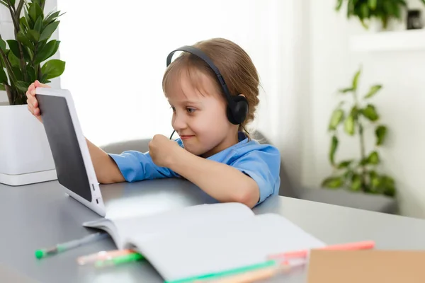 Schattig klein meisje zit aan tafel met haar laptop en studeren online — Stockfoto