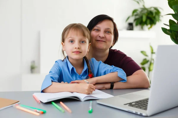 Lessen op afstand. Het kind glimlacht vrolijk en krijgt op afstand kennis. Meisje studeert online leren van thuis. Online school. — Stockfoto