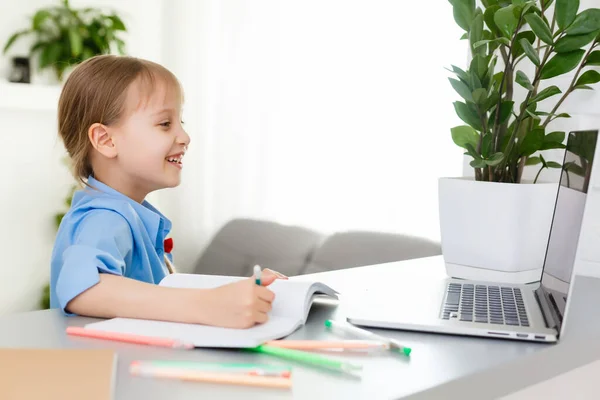 Menina bonito está sentado à mesa com seu laptop e estudando on-line — Fotografia de Stock