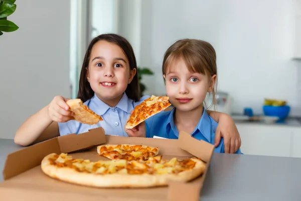 Zwei glückliche kleine Freundinnen essen Pizza-Scheiben. — Stockfoto