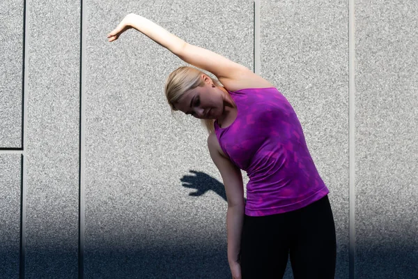 Deporte de fitness mujer en ropa deportiva de moda haciendo yoga ejercicio de fitness en la calle, deportes al aire libre, estilo urbano — Foto de Stock