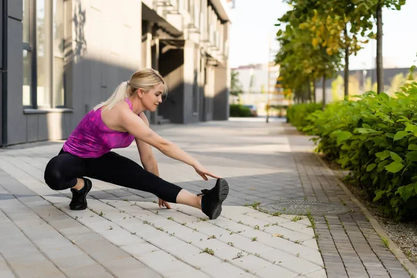 Mujer del deporte haciendo ejercicio de estiramiento durante el entrenamiento de entrenamiento cruzado al aire libre — Foto de Stock