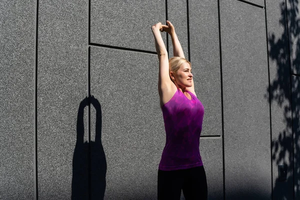 Спортивная женщина делает упражнения на растяжку во время тренировки на открытом воздухе — стоковое фото