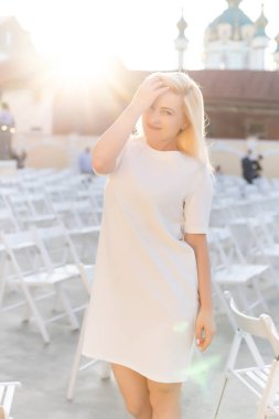 Yazın beyaz elbiseli çekici bir kadın açık hava tiyatrosunda tek başına, Spring Street tarzı moda trendi, sosyal mesafeli.