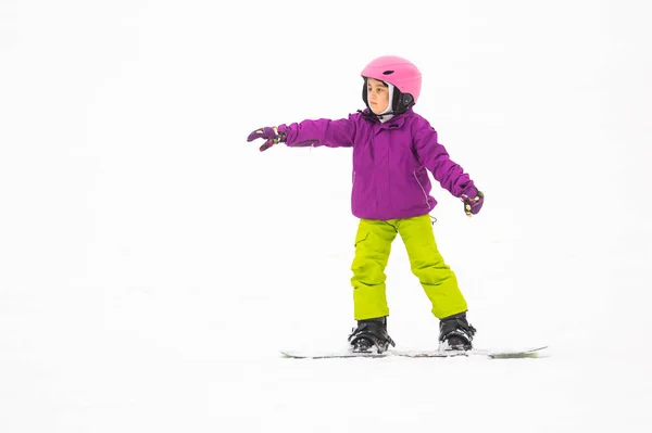 Petite fille mignonne Snowboard à la station de ski dans une journée ensoleillée d'hiver. — Photo