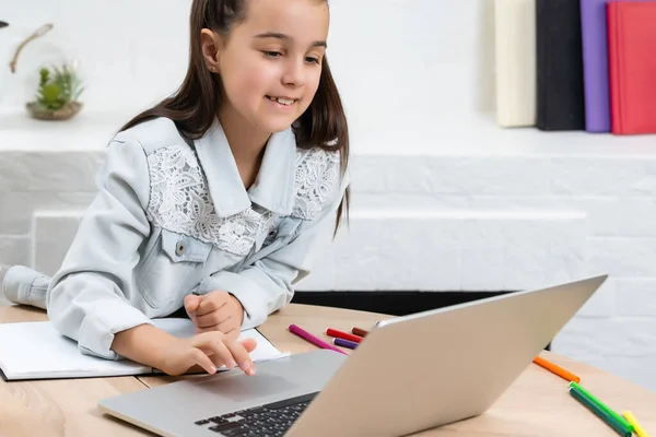 Crianças, educação e conceito de aprendizagem distante, pequena menina estudante com computador portátil em casa — Fotografia de Stock