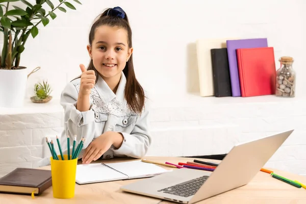 Closeup foto de pouco aluno bonita escola senhora falar skype notebook online aula vídeo chamada sit desk uso fones de ouvido distância cumprimentar colegas de classe quarentena estudo sala de estar dentro de casa — Fotografia de Stock