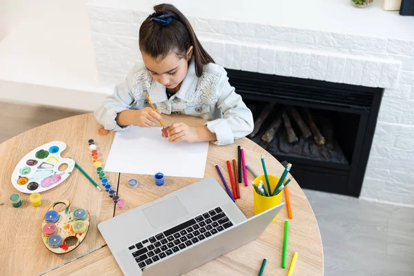 Jong meisje besteedt een tijd aan tekenen met behulp van online lessen op laptop. Online onderwijs op afstand — Stockfoto