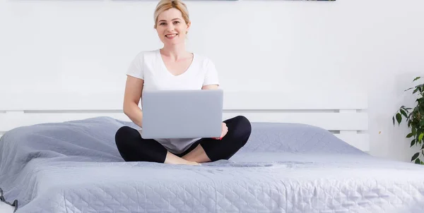 Mujer usando un ordenador portátil mientras se relaja en el sofá — Foto de Stock