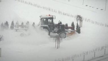 Traktör kazıcı şehir bahçesindeki karı kaldırıyor. kamu hizmetlerinin çalışması