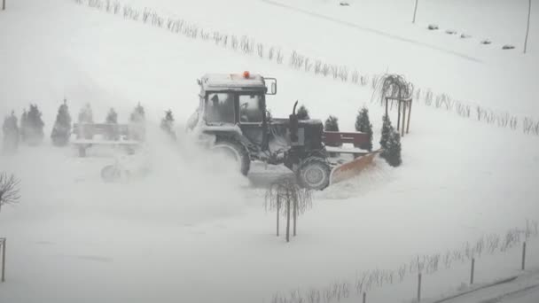 Ciągnik koparka usuwa śnieg na dziedzińcu miasta. prace przedsiębiorstw użyteczności publicznej — Wideo stockowe