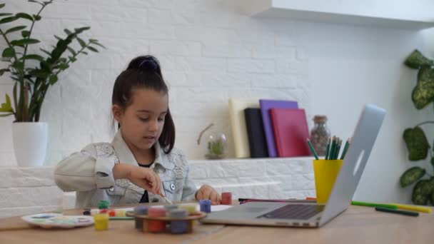 Sérieux petite fille écriture étude en ligne à l'aide d'un ordinateur portable à la maison, mignon heureux petit enfant prendre Internet leçon web ou classe — Video