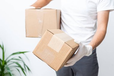 Karton kutuları tıbbi lastik eldiven ve maskeyle taşıyan teslimatçı. kopyalama alanı. Hızlı ve ücretsiz teslimat. İnternetten alışveriş ve ekspres teslimat. Karantina