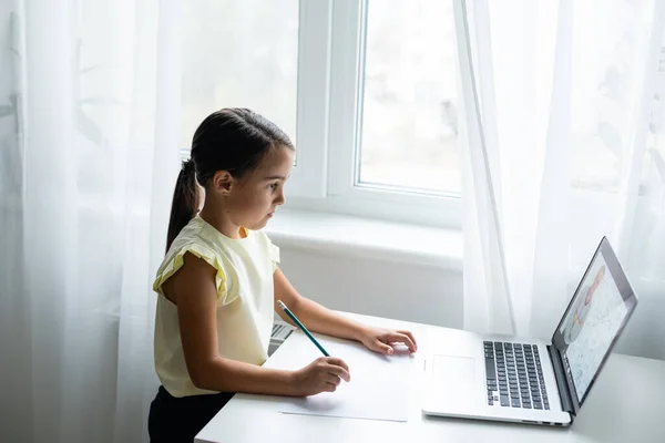 Klein meisje op zoek naar laptop scherm met expressie van verrast en opwinding. Slim, lachend meisje dat aantekeningen maakt. Communicatie in het bedrijfsleven. — Stockfoto