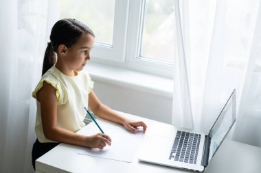 ev, eğlence, teknoloji ve internet konsepti - evde dizüstü bilgisayarı olan küçük kız, küçük kız görüntülü sohbet kullanıyor