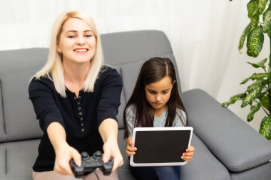 Mutlu bir aileyiz. Anne ve kız çocuğu video oyunu oynuyorlar. Aile rahatlar.