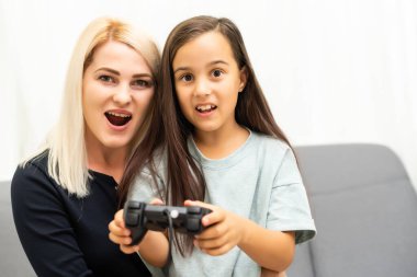Mutlu bir aileyiz. Anne ve kız çocuğu video oyunu oynuyorlar. Aile rahatlar.