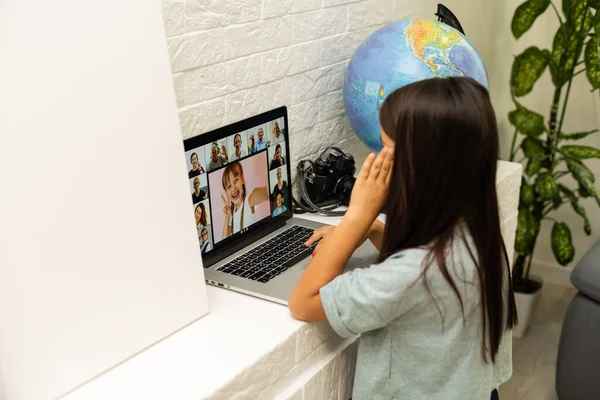 Menina minúscula olhando para a tela do laptop com expressão de surpresa e emoção. Uma menina esperta e sorridente a tirar apontamentos. Comunicação no conceito de negócio. — Fotografia de Stock