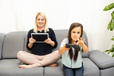Mutlu bir aileyiz. Anne ve kız çocuğu video oyunu oynuyorlar. Aile rahatlar.