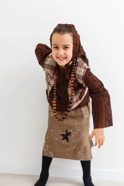 Retrato de niña divertida vestida como una vieja bruja posando con escoba delante de fondo blanco — Foto de Stock