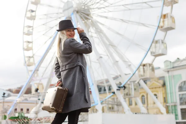 Jeune femme portant un chapeau marchant à l'extérieur sur la rue de la ville près de la roue ferris souriant gai. — Photo