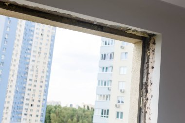 Geniş panoramik pencereye boş çerçeve. Çok katlı bir apartmanın penceresinden muhteşem bir manzara. Çatılar dolusu ev ve ağaçlar. Pencereden manzara çok güzel. Çerçeve