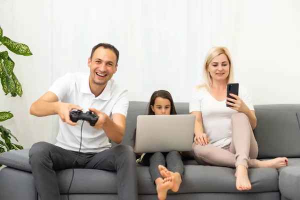 Glückliche Familie sitzt auf einem Sofa und spielt Videospiele. — Stockfoto