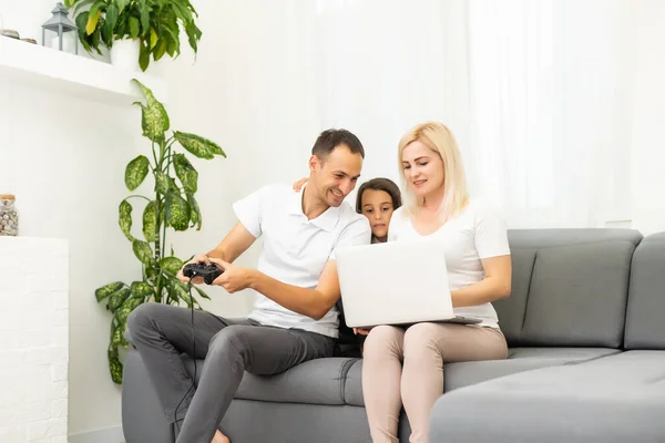 Joyeux famille assis sur un canapé et jouant à des jeux vidéo. — Photo