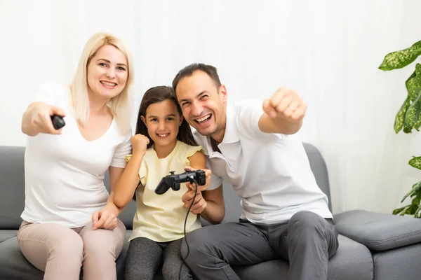 Familia feliz sentada en un sofá y jugando videojuegos. — Foto de Stock