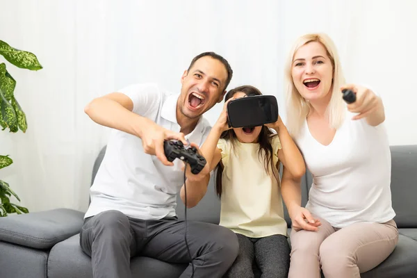 Famiglia felice seduta su un divano e giocare ai videogiochi. — Foto Stock