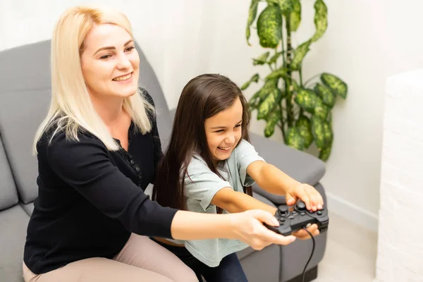 Madre e hija sentadas en una sala de juegos, jugando videojuegos y divirtiéndose. — Foto de Stock