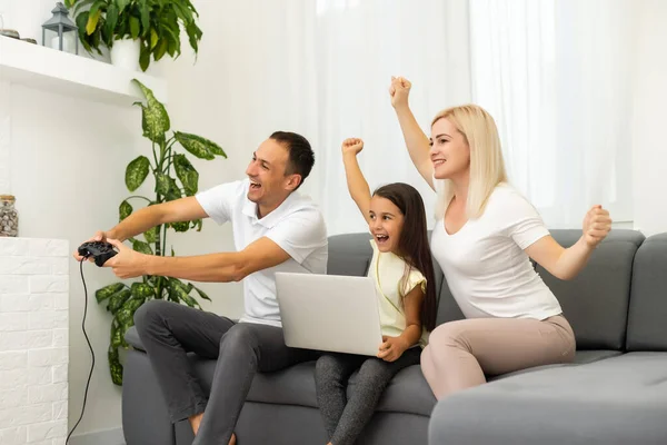 Famiglia felice seduta su un divano e giocare ai videogiochi. — Foto Stock