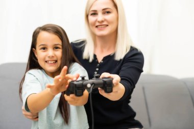 Mutlu bir aileyiz. Anne ve kız çocuğu video oyunu oynuyorlar. Aile rahatlar.