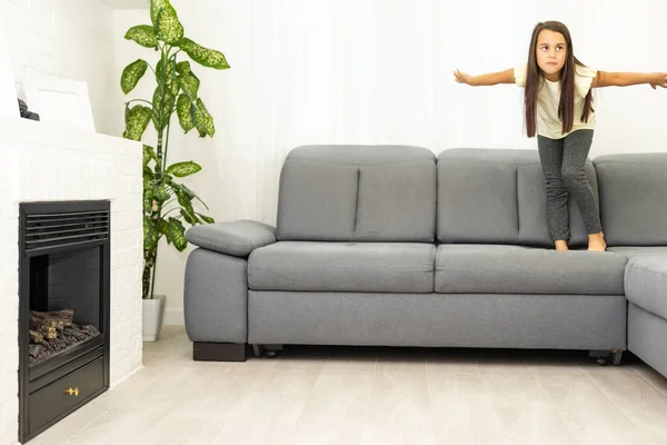 Söt liten flicka skrattar när du spelar på soffan hemma — Stockfoto