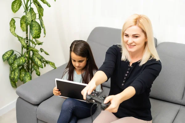 Mutter und tochter sitzen im spielzimmer, spielen videospiele und haben spaß. — Stockfoto