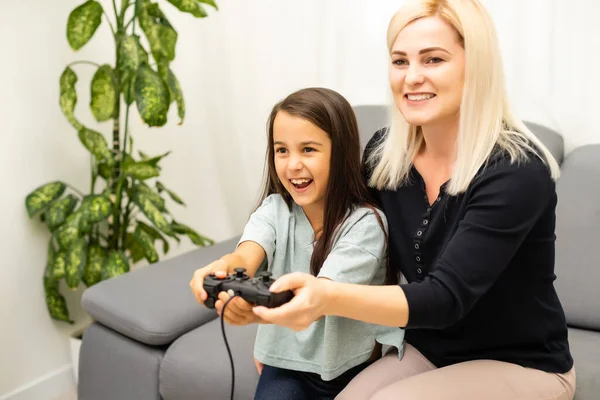 Madre e figlia seduta in una sala giochi, giocare ai videogiochi e divertirsi. — Foto Stock