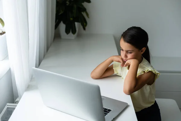 Litttle flicka tittar på bärbar skärm med uttryck av förvånad och upphetsning. Smart, smilande liten flicka som antecknade. Kommunikation i affärsidén. — Stockfoto