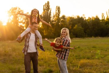 Mutlu aile: anne baba ve kız gün batımında doğada