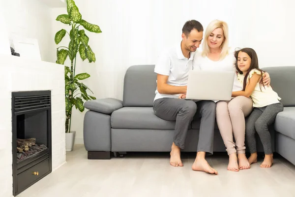 Familjeshoppning online. Glad familj ler medan du sitter på soffan och handlar online tillsammans — Stockfoto