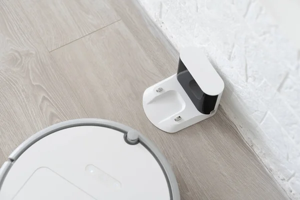 Білий роботизований пилосос на ламінатній підлозі очищає пил в інтер'єрі вітальні. Розумна технологія домогосподарства . — стокове фото