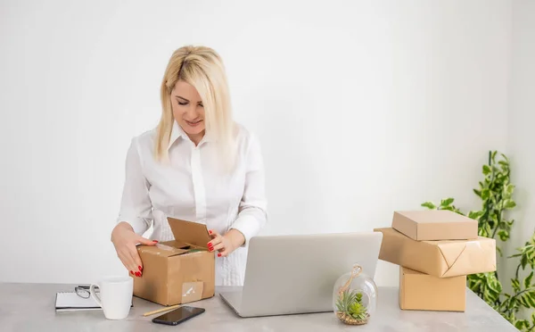 Jeune femme préparant des enveloppes de colis pour l'expédition au client au bureau à domicile, boîte — Photo