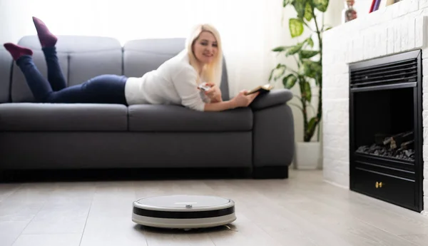 Robotic dammsugare städa rummet medan kvinnan sitter på soffan, närbild — Stockfoto