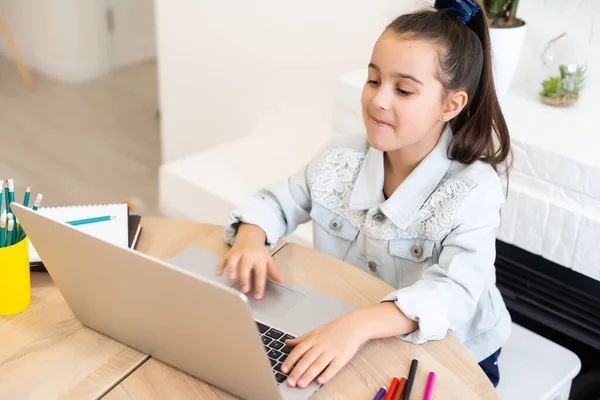Küçük kız ödevini evde yapıyor ve dizüstü bilgisayar kullanıyor. — Stok fotoğraf