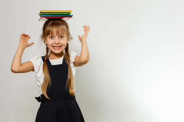 Egy kis vicces lány pólóban könyvekkel. Elszigetelve, fehér háttérrel. Kislány az iskolában. A kislány a tankönyvekkel. Csajozás. — Stock Fotó