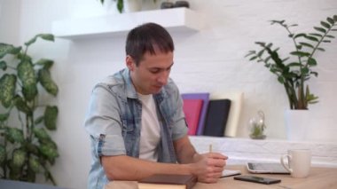 Evdeki masada tabletle çalışan adam.