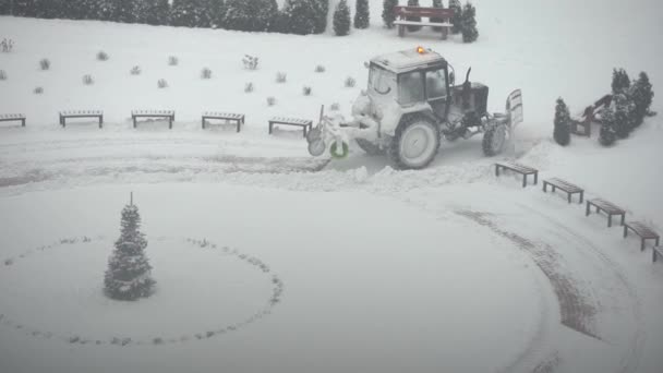 Traktor-grävmaskinen tar bort snö på innergården. arbete inom allmännyttiga företag — Stockvideo