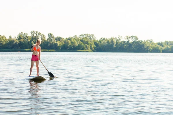 Jovem mulher atraente em pé paddle board no lago, SUP — Fotografia de Stock