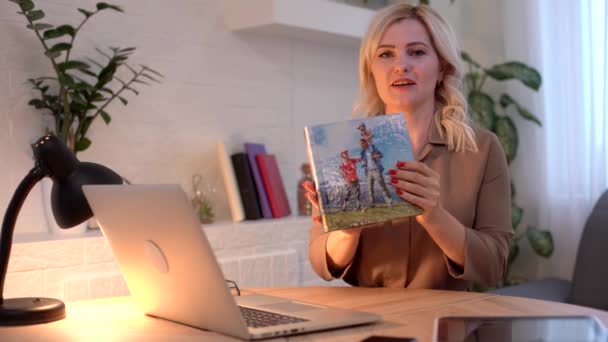 Nahaufnahme Junge Frau schaut Fotobuch an, Frau präsentiert Fotobuch in der Nähe von Laptop — Stockvideo