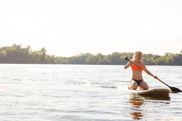 En vacker kvinna övar paddla på en vacker solig dag — Stockfoto